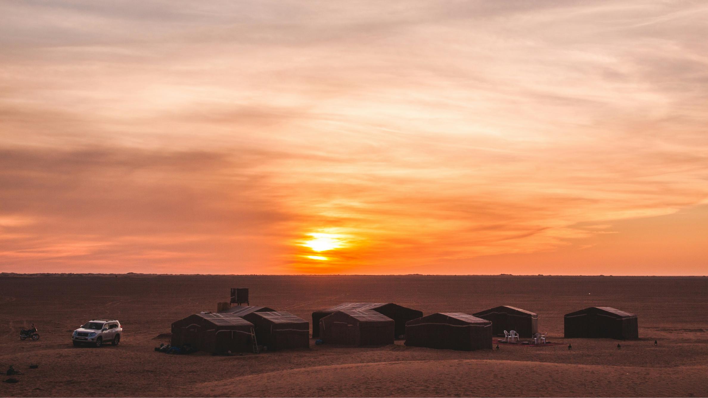 Camel caravan crossing the dunes at sunset during a desert trek in Mhamid